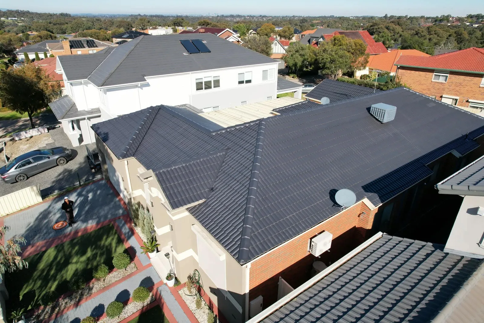 Aerial view of a freshly restored charcoal tile roof on a two-storey home in a dense suburban street